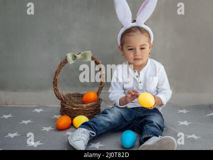 Cute Little Boy Dressed as a Bunny Playing with Decorations. Kid with Colorful Easter Eggs. Happy Easter. Spring Christian Holiday. Stock Photo