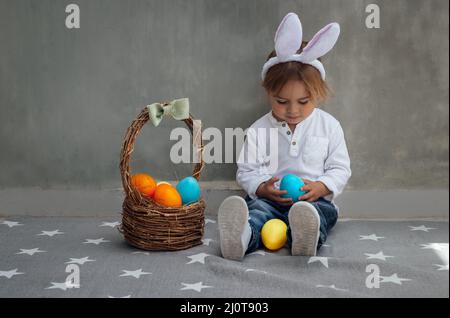 Cute Little Boy Dressed as a Bunny with Basket Full of Colorful Easter Eggs. Egg Hunting. Happy Christian Spring Holiday. Stock Photo