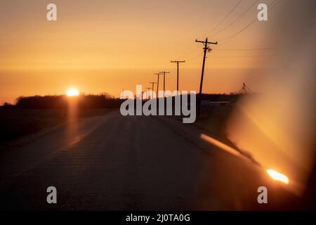 Telephone poles along a rural road in the American Midwest at sunset Stock Photo