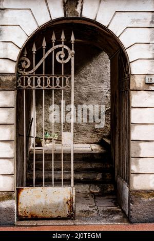 Wrought-iron gate with sharp prongs in the arched entrance to the building Stock Photo