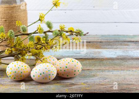 Easter composition of flowering twigs of willow, dogwood and Easter eggs with a pattern of yellow dots on a wooden retro backgro Stock Photo
