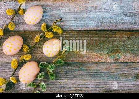 Easter composition of blooming willow twigs and Easter eggs with a pattern of yellow dots on a wooden retro background with copy Stock Photo