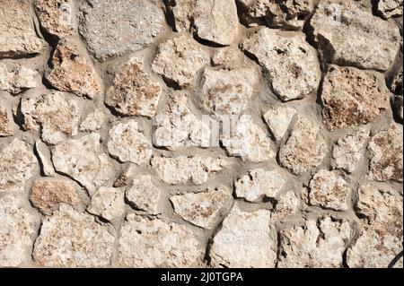 The stone wall is lined with natural stone and cemented. Natural building material. Medieval background Stock Photo