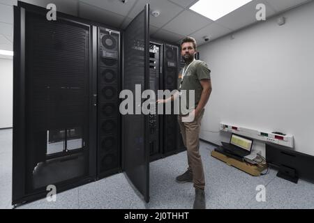 Data Center Engineer Usaing Keyboard on a Supercomputer Server Room Specialist Facility with Male System Administrator Stock Photo