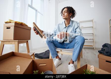 handsome guy unpacking things from boxes in the room interior Stock