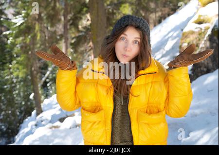 Shrugging doubting young woman in winter clothes shrugs, attractive embarrassed girl gesturing, does not know, in winter snowy f Stock Photo