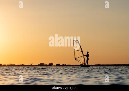 Silhouette of a young woman kitesurfer at sunset. Trainings in calm weather on the estuary Stock Photo