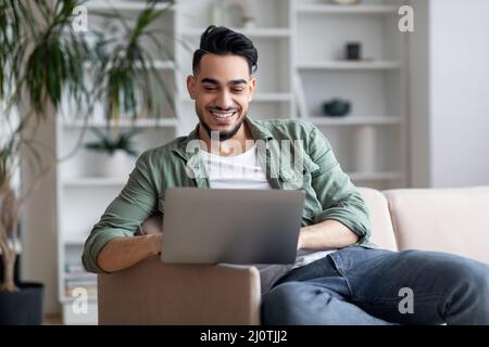 Portrait Of Handsome Young Middle Eastern Guy Using Laptop At Home Stock Photo
