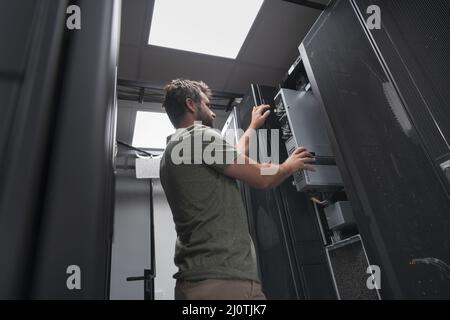 IT engineer working In the server room or data center The technician puts in a rack a new server of corporate business mainframe Stock Photo