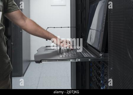 Close up on Data Center Engineer hands Using keyboard on a supercomputer Server Room Specialist Facility with Male System Admini Stock Photo