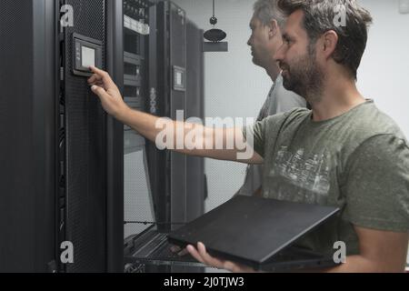 Technicians team updating hardware inspecting system performance in super computer server room or cryptocurrency mining farm. Stock Photo