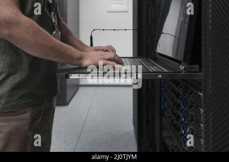 Close up on Data Center Engineer hands Using keyboard on a supercomputer Server Room Specialist Facility with Male System Admini Stock Photo