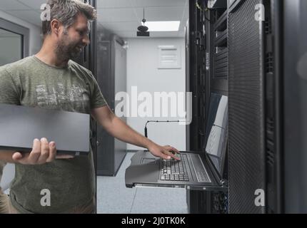 Close up on Data Center Engineer hands Using keyboard on a supercomputer Server Room Specialist Facility with Male System Admini Stock Photo