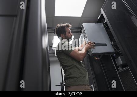 IT engineer working In the server room or data center The technician puts in a rack a new server of corporate business mainframe Stock Photo