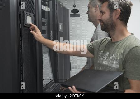 Technicians team updating hardware inspecting system performance in super computer server room or cryptocurrency mining farm. Stock Photo
