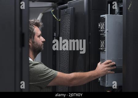 IT engineer working In the server room or data center The technician puts in a rack a new server of corporate business mainframe Stock Photo