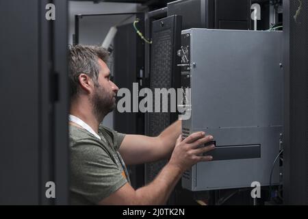 IT engineer working In the server room or data center The technician puts in a rack a new server of corporate business mainframe Stock Photo