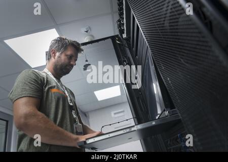 Close up on Data Center Engineer hands Using keyboard on a supercomputer Server Room Specialist Facility with Male System Admini Stock Photo