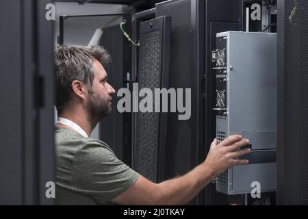 IT engineer working In the server room or data center The technician puts in a rack a new server of corporate business mainframe Stock Photo