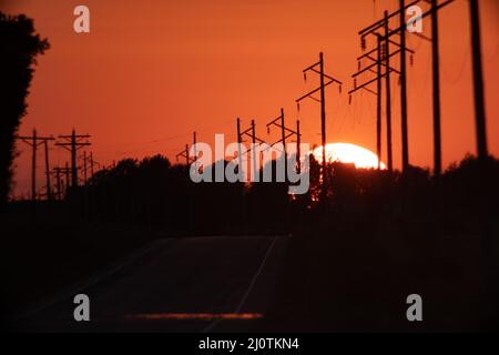 Big Sun Setting Over Highway Next to Powerlines Stock Photo