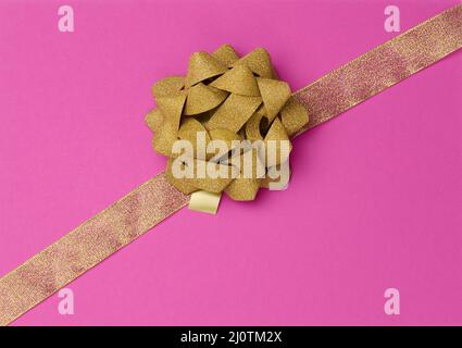 Bow and golden silk ribbon on a pink background, design element for gift decor, line Stock Photo