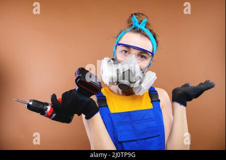 Portrait of a caucasian young woman in the uniform of a superintendent of streetwear in overalls, respirator and goggles with a Stock Photo
