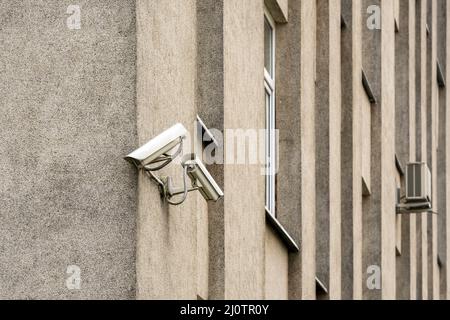 Two CCTV cameras on grey building wall Stock Photo