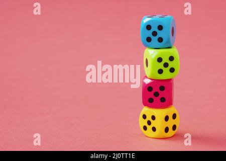 Stack of colorful dice on pink background Stock Photo