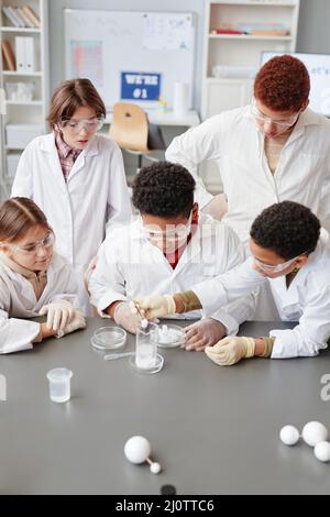 High angle view at diverse group of children enjoying science experiments in chemistry class and wearing lab coats Stock Photo