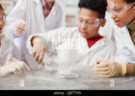 Close up of foaming liquid in beaker glass on table in school chemistry lab, copy space Stock Photo