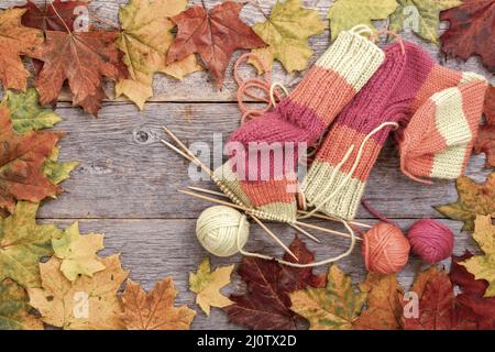 Knitted sock, balls of yarn and knitting needles on rustic table Stock Photo