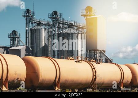 Grain silo, warehouse or depository next to railroad tracks with set of train tanks Stock Photo