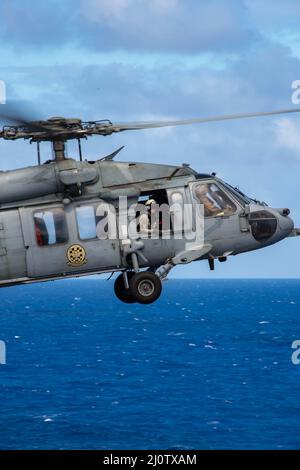 220128-N-PV401-1008 PHILIPPINE SEA (Jan. 28, 2022) An MH-60S Sea Hawk, assigned to the “Black Knights” of Helicopter Sea Combat Squadron (HSC)4, flies over Nimitz-class aircraft carrier USS Carl Vinson (CVN 70), Jan. 28, 2022. Carl Vinson Carrier Strike Group is on a scheduled deployment in the U.S. 7th Fleet area of operations to enhance interoperability through alliances and partnerships while serving as a ready-response force in support of a free and open Indo-Pacific region. (U.S. Navy photo by Mass Communication Specialist Seaman Elizabeth Grubbs) Stock Photo