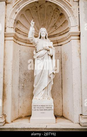 Statue of Jesus Christ with a book in hands near the Church of the Nativity of the Virgin in Prcanj Stock Photo