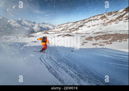 Skier rides on a snowy slope on a sunny day at sunset against the backdrop of the mountains. The concept of winter skiing