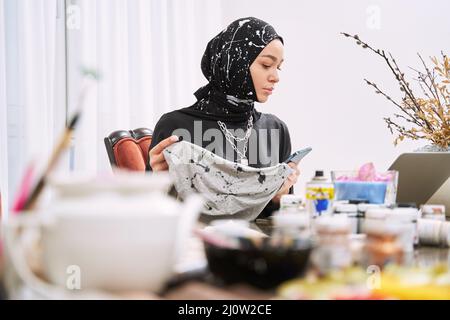 Young muslim woman sewing traditonal clothes in modern studio Stock Photo