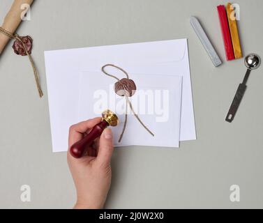 Sealed white envelope with brown wax seal on beige background, flat lay Stock Photo
