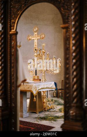 Branched gold candlestick on a table in front of a cross in the Church of St. Sava in Tivat. Montenegro Stock Photo