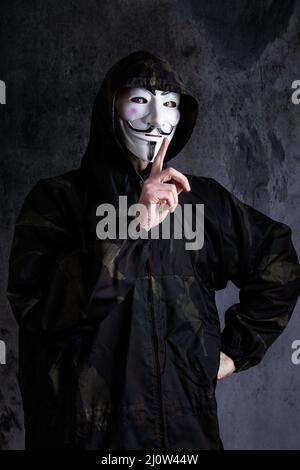Midsection of a man wearing the mask of anonymous / Guy Fawkes and a camouflage uniform Stock Photo
