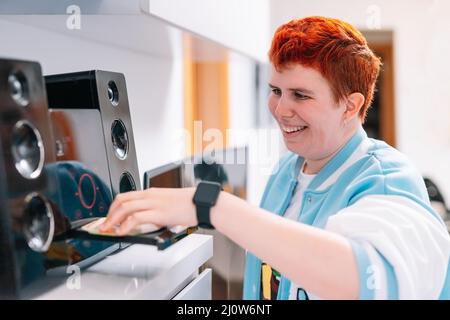 non-binary gender playing a CD on his mini-system to listen to music. Stock Photo