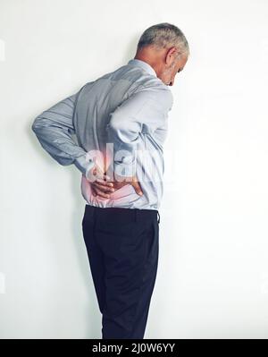 Back pain is getting the better of him. Studio shot of a mature man experiencing muscular strain. Stock Photo