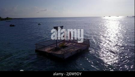 Couple relaxing on a sunbathing wooden raft in the Rasdhoo Island, The Maldives Stock Photo