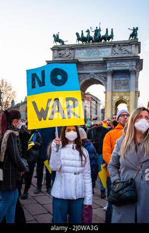 Milan, Italy - 03 19 2022: demonstration against Ukraine war at Peace Arch, Arco della Pace, illuminated with Ukraine flag colors, yellow and blue Stock Photo