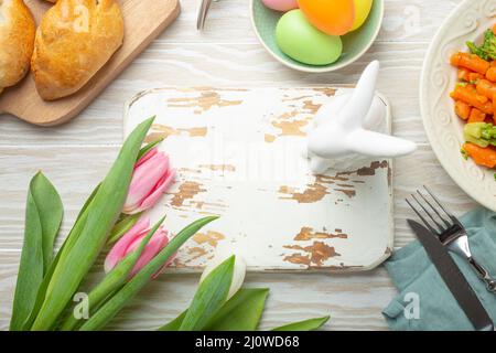 White empty wooden cutting board and Easter food on kitchen table Stock Photo