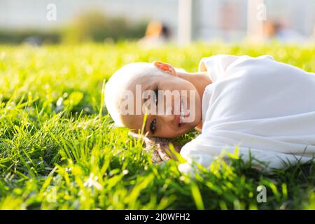Millenial young woman blonde short hair outdoor smiling lay on grass portrait.