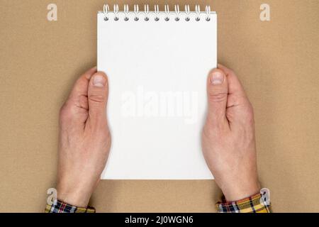 Hands holding a spiral notebook with blank sheets for writings Stock Photo