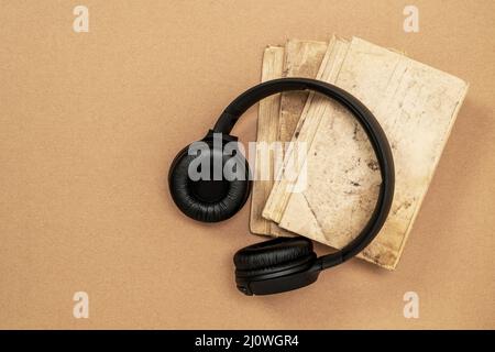 Top view of black headphones and books on cardboard background Stock Photo