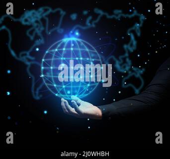 A man's hand holds a holographic globe on a dark blue background. Concept of globalization, world internet network, barrier-free Stock Photo