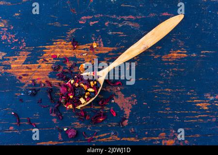 Wooden spoon with dried flower berry tea on an old black wooden background top view Stock Photo