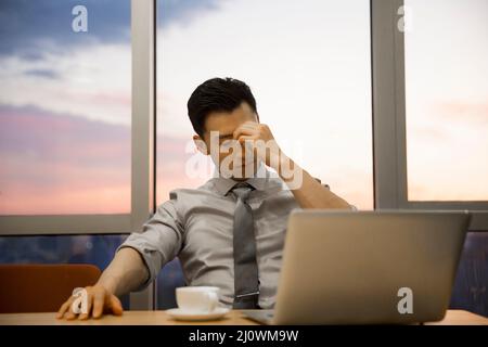 Tired Chinese young business man works in office Stock Photo